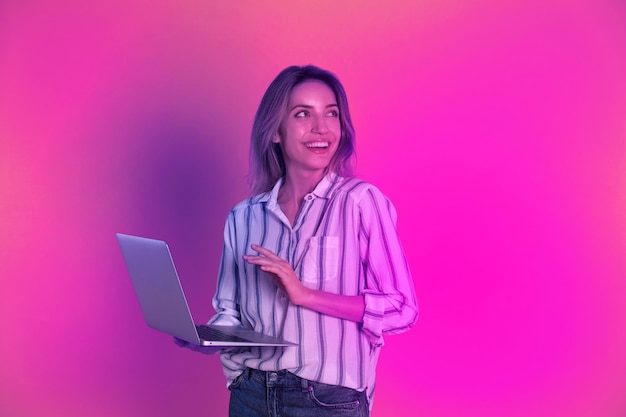 Mujer joven con una computadora portátil moderna en fondo amarillo