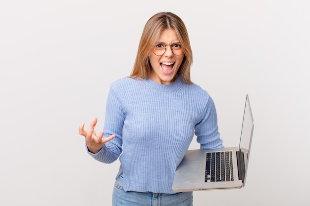 Mujer joven con una computadora portátil que parece enojada, molesta y frustrada