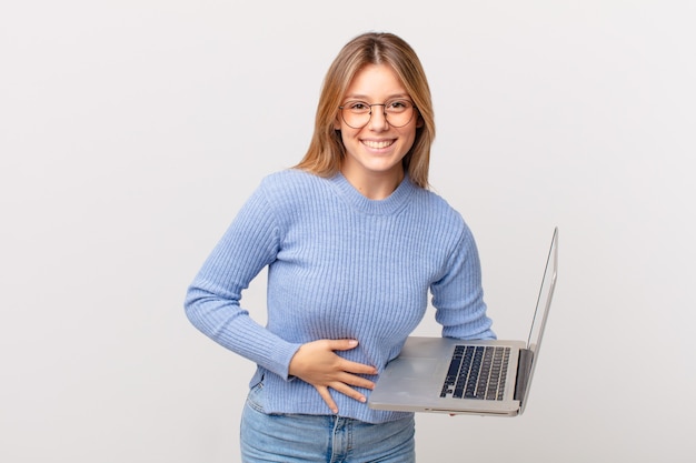 Mujer joven con una computadora portátil riéndose a carcajadas de una broma hilarante