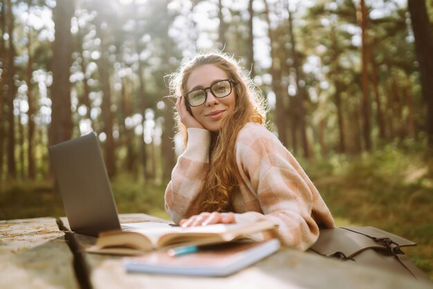 Mujer joven con computadora portátil trabajando o estudiando en línea al aire libre Blogging de negocios videoconferencia