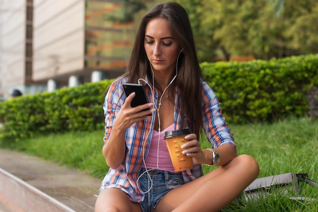 Mujer joven concentrada escribiendo un mensaje de texto en su teléfono móvil al aire libre Mujer seria usando un teléfono inteligente