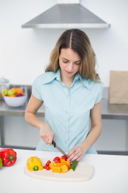 Mujer joven concentrada en verduras de corte de cocina