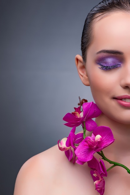 Mujer joven en concepto de belleza con flor de la orquídea