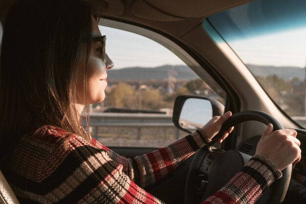 Mujer joven conduce un coche.