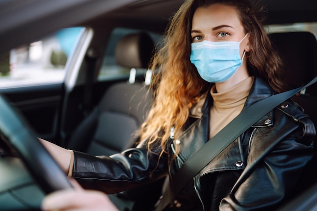 Mujer joven conduciendo un automóvil con una máscara médica durante una epidemia Aislamiento de transporte Covid2019