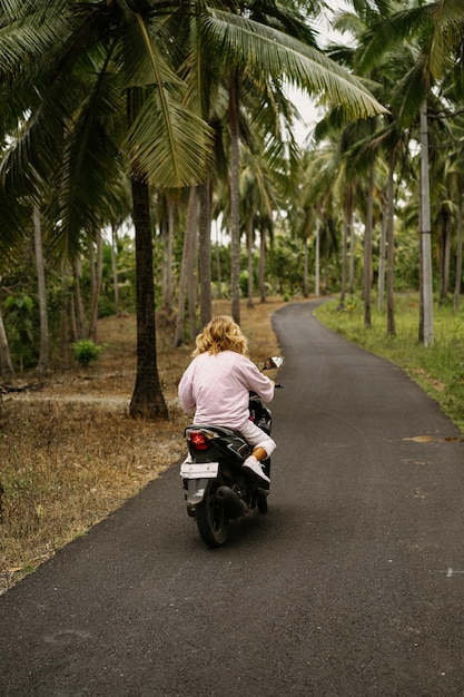 mujer joven conduciendo un ciclomotor vida tropical