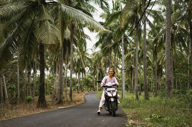 mujer joven conduciendo un ciclomotor vida tropical