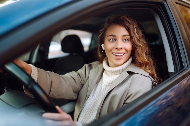 Mujer joven conduciendo un coche en la ciudad Servicio de alquiler de coches compartidos o aplicación de taxi