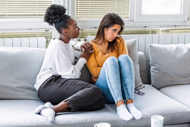 Mujer joven consolando a su amiga en casa