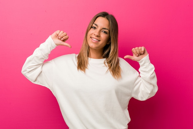 Mujer joven contra una pared apuntando a sí misma