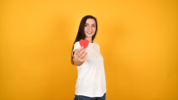 Mujer joven, con, corazón, en, manos, en, amarillo