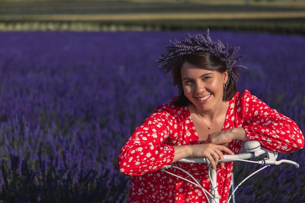 Una mujer joven con una corona en la cabeza se sienta en una bicicleta en un campo de lavanda