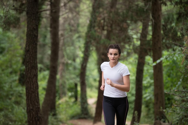 Mujer joven corriendo en el área boscosa del bosque entrenando y haciendo ejercicio para Trail Run Marathon Endurance Fitness Concepto de estilo de vida saludable