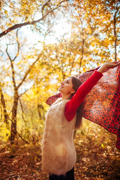 Mujer joven corriendo con una bufanda en el bosque de otoño