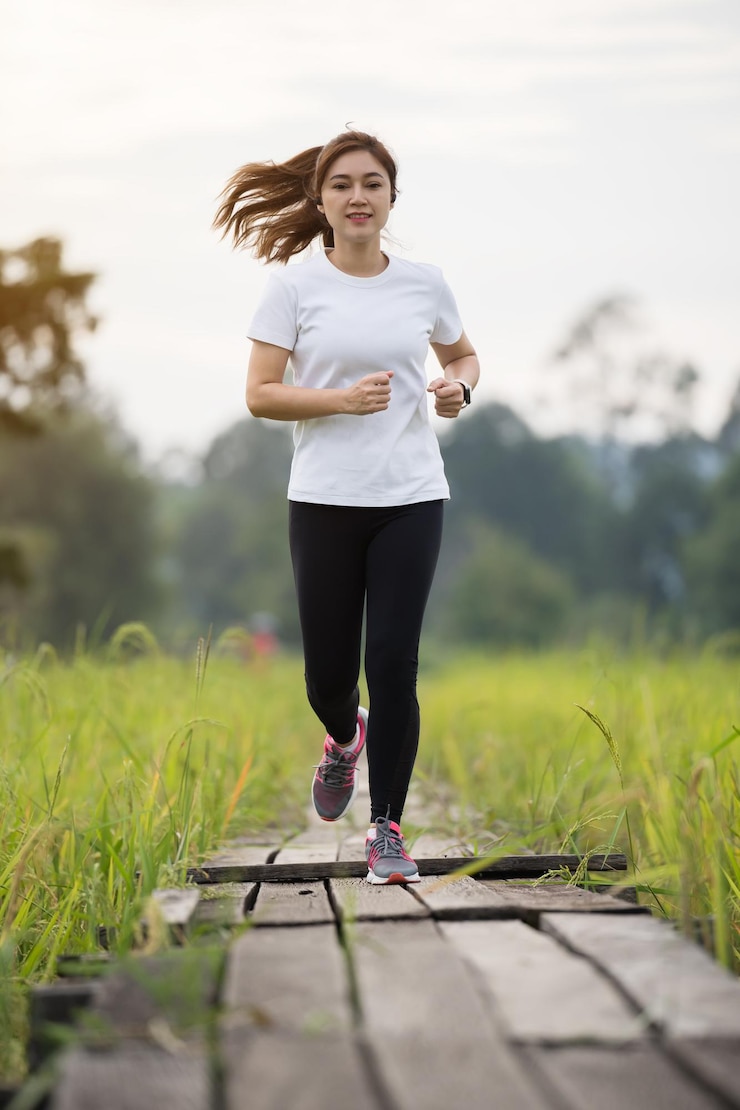 Foto mujer joven corriendo por un camino de madera en el campo