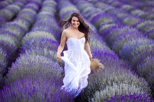 Mujer joven corriendo en el campo de lavanda. Hermosa mujer sobre fondo floral de verano