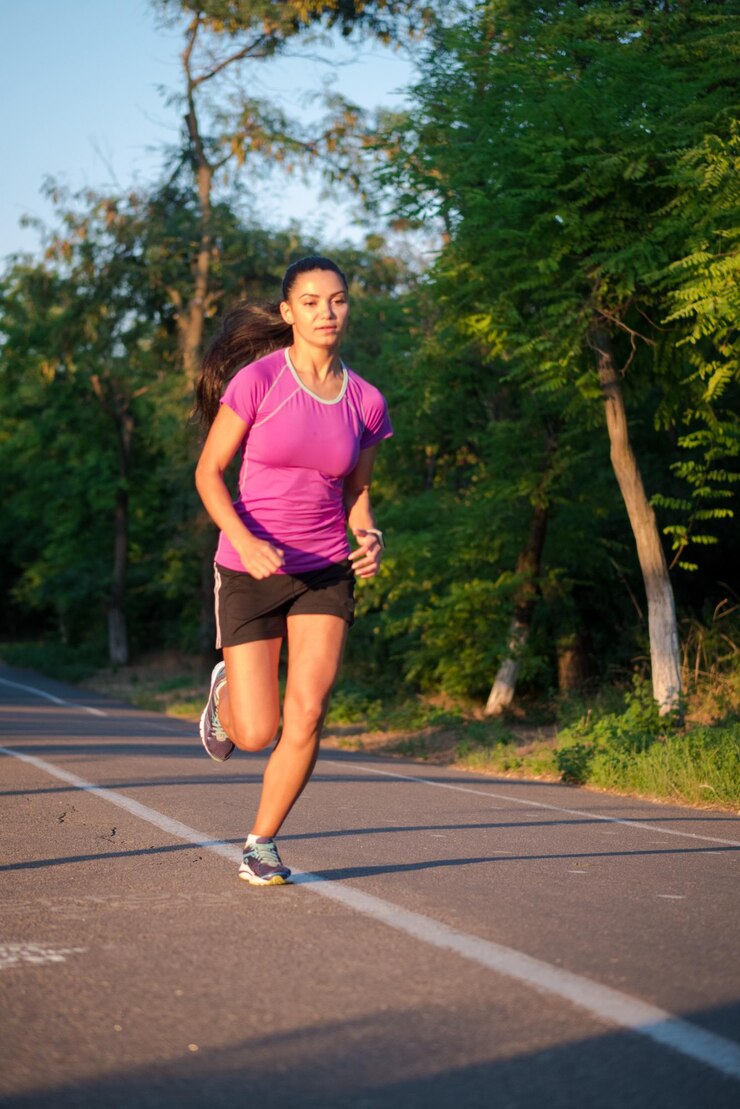 Foto mujer joven corriendo por la carretera en medio de los árboles