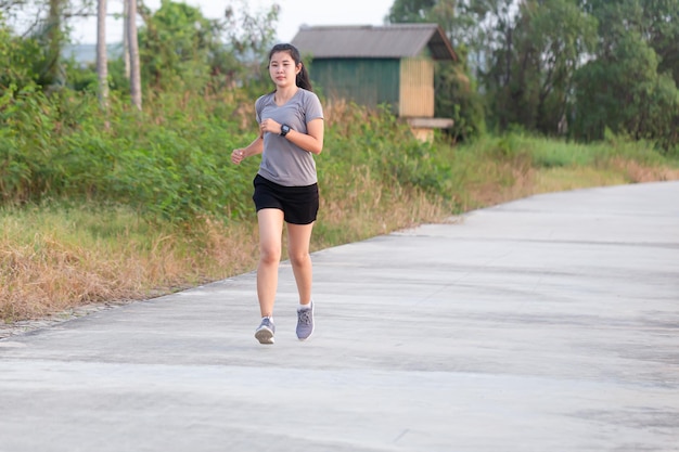 Mujer joven corriendo durante la mañana soleada en la pista del estadio