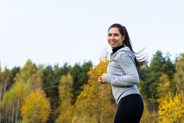 Foto mujer joven corriendo en el parque durante el otoño