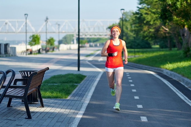 Mujer joven corriendo en pista durante la sesión de entrenamiento Corredora practicando en pista de carreras de atletismo