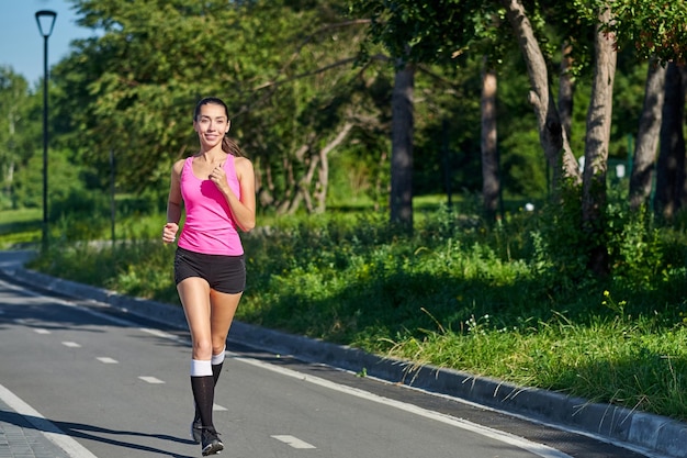 Mujer joven corriendo en pista durante la sesión de entrenamiento Corredora practicando en pista de carreras de atletismo