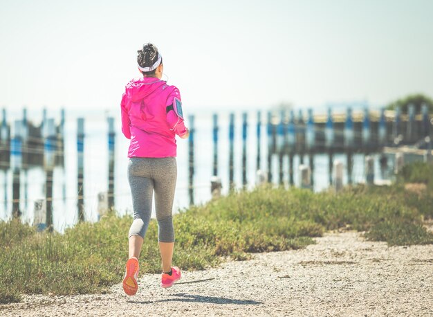 Mujer joven corriendo en la playa concepto mujer entrenamiento bienestar fitness jog imagen tonificada