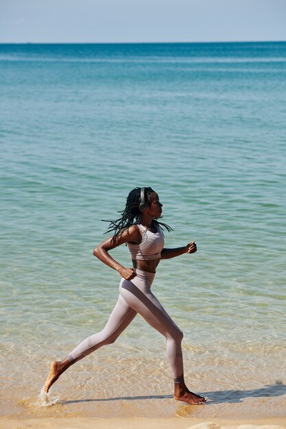 Mujer joven corriendo por la playa