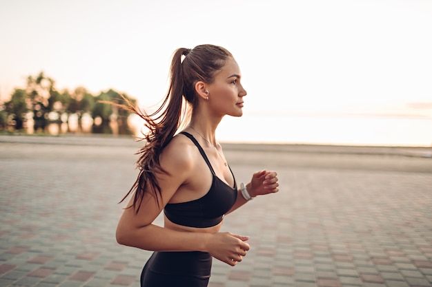 Mujer joven corriendo por el río al amanecer.