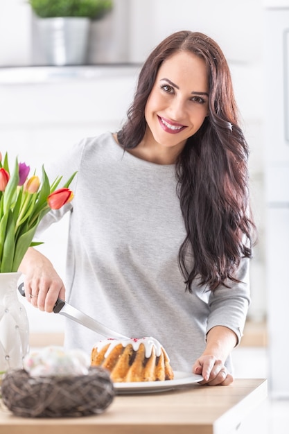 Mujer joven cortando pastel de Pascua dulce durante las vacaciones.