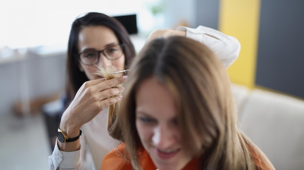 Foto mujer joven cortando las puntas de su cabello con tijeras a su amiga en casa de cerca