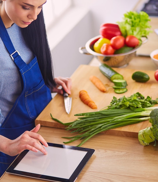 Mujer joven cortando verduras en la cocina de casa