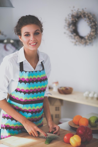 Foto mujer joven, corte, vegetales, en, cocina, en el escritorio