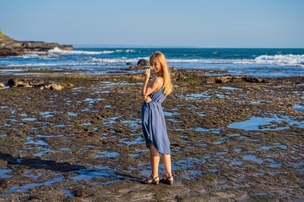 Una mujer joven en una costa cósmica rocosa de Bali