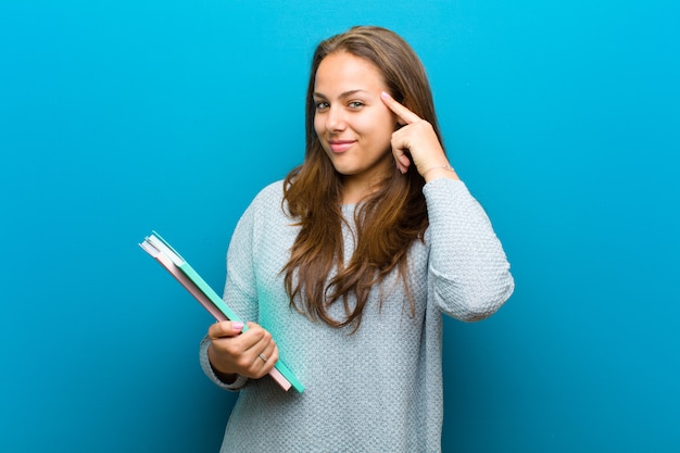 Mujer joven con un cuaderno sobre fondo azul