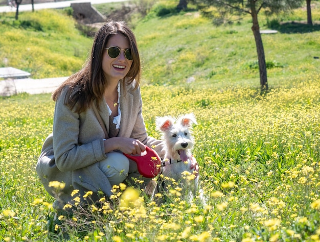 Mujer joven en cuclillas mira a la cámara con su perro schnauzer