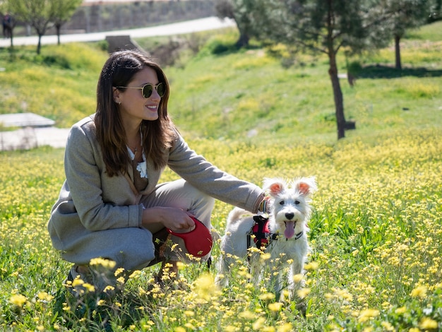 Mujer joven en cuclillas con su perro schnauzer