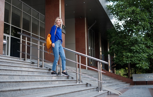 Mujer joven de cuerpo completo caminando por pasos después de las lecciones universitarias