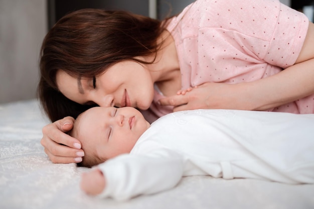 Mujer joven cuidando a su hija dormida en el dormitorio