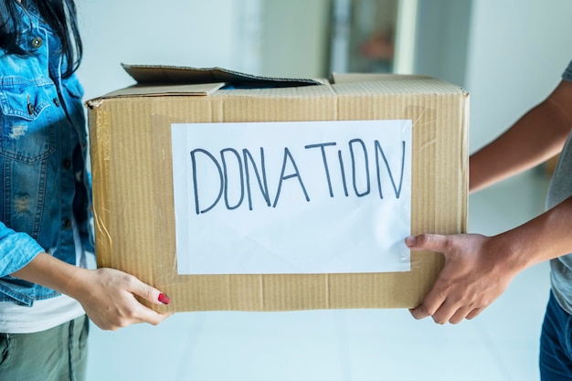 Mujer joven dando una caja de donaciones a un voluntario