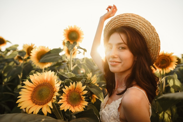 Mujer joven dando un paseo en el campo de girasoles en la mañana