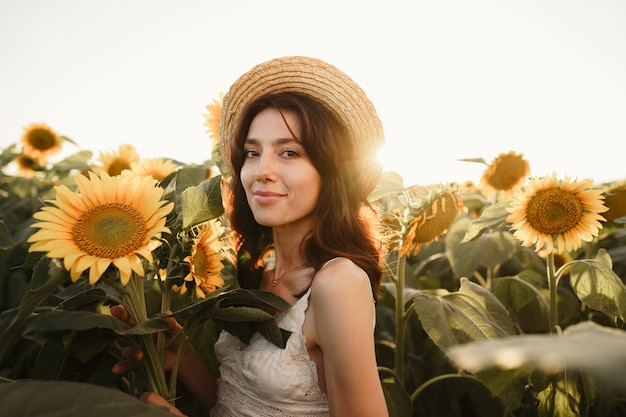 Mujer joven dando un paseo en el campo de girasoles en la mañana