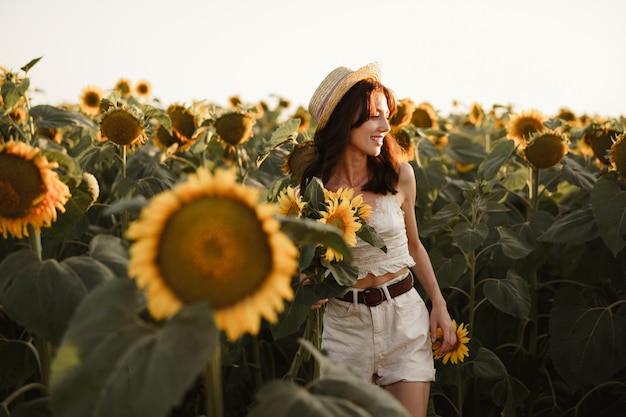 Mujer joven dando un paseo en el campo de girasoles en la mañana