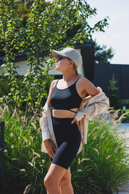 Mujer joven y delgada con estilo en un top negro y pantalones cortos con una chaqueta de gran tamaño Una chica con estilo camina por la calle elegante traje de moda de verano gafas de sol