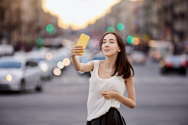 Mujer joven delgada toma selfie durante caminar