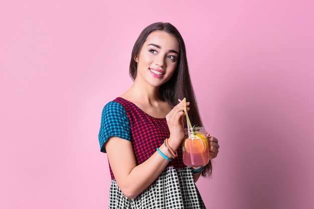 Mujer joven con deliciosa limonada refrescante en color