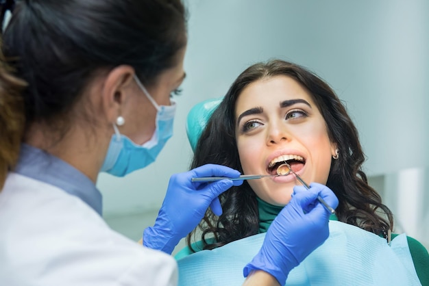 Mujer joven en el dentista Estomatólogo sosteniendo un espejo cóncavo Revise sus dientes