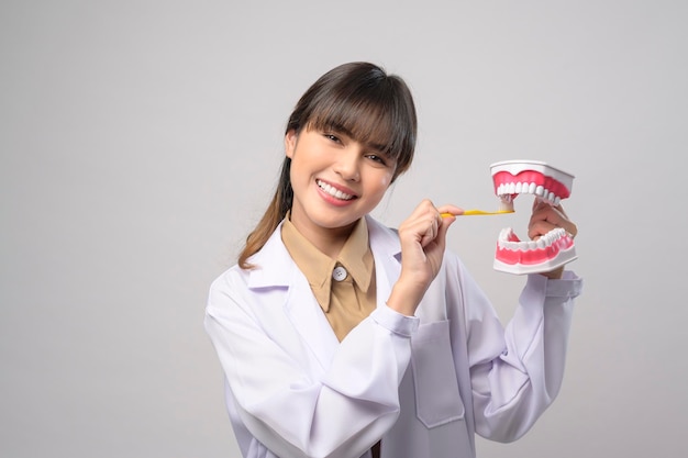 Mujer joven dentista sonriendo sobre fondo blanco studio