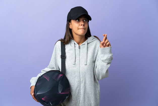 Mujer joven deporte con bolsa de deporte con los dedos cruzando y deseando lo mejor