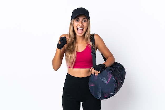 Mujer joven deporte con bolsa de deporte sobre fondo blanco aislado celebrando una victoria en la posición ganadora