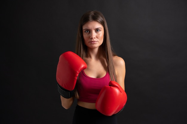 Mujer joven deporte con guantes de boxeo sobre negro aislado